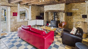 A cozy room with a red sofa, a black leather couch, and a checkered floor. - In the heart of the village, house for 8 with pool (Coly)