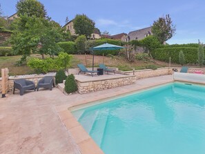 A swimming pool with lounge chairs and a stone wall. - In the heart of the village, house for 8 with pool (Coly)
