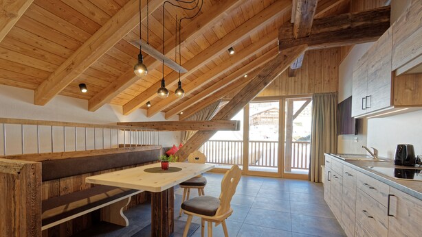 A kitchen with wooden beams, a bench, a table, and a chair. - Vacation apartment "Tischlerhof Stadl" (St.Jakob/Ahrntal)
