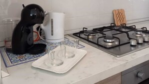 Una cocina con estufa a gas, hervidor y cafetera.