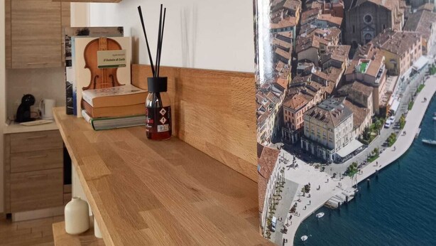 Una barra de madera con un libro titulado 'Il libro di Salò' y una botella de líquido rojo, probablemente una salsa, en un recipiente de vidrio.