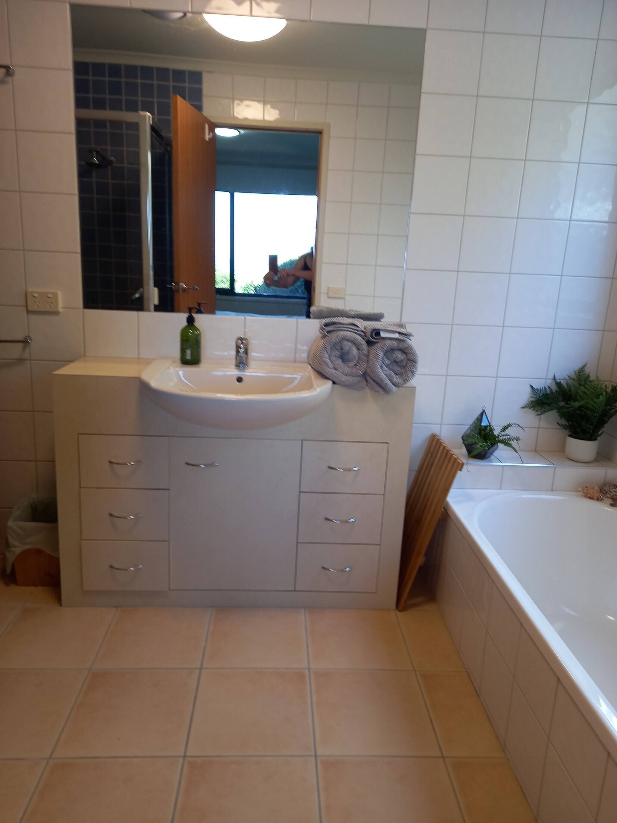 A modern bathroom with a white sink, mirror, and a bathtub.
