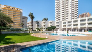 A hotel with a swimming pool, surrounded by greenery and tall buildings. - Praia da Rocha/1605/Charming Apart/Sea View/by IG (Portimão)