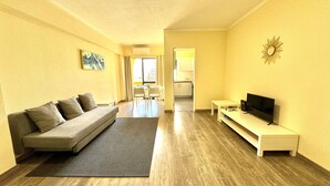 Un espacio habitable compacto con sofá, televisor de pantalla plana y comedor con sillas y mesa.