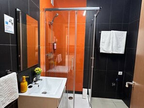 Un baño moderno con cabina de ducha de vidrio, lavabo blanco y espejo.