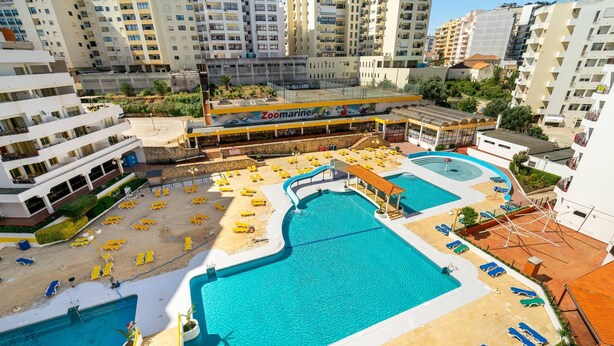 Un espace piscine sur le toit, comprenant plusieurs piscines, des chaises longues et un restaurant Zoomarine.