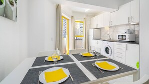 Une cuisine moderne avec des meubles blancs, un four à micro-ondes et un lave-linge.