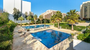 Ein Poolbereich mit zwei Pools, umgeben von Palmen und einem gepflasterten Weg.