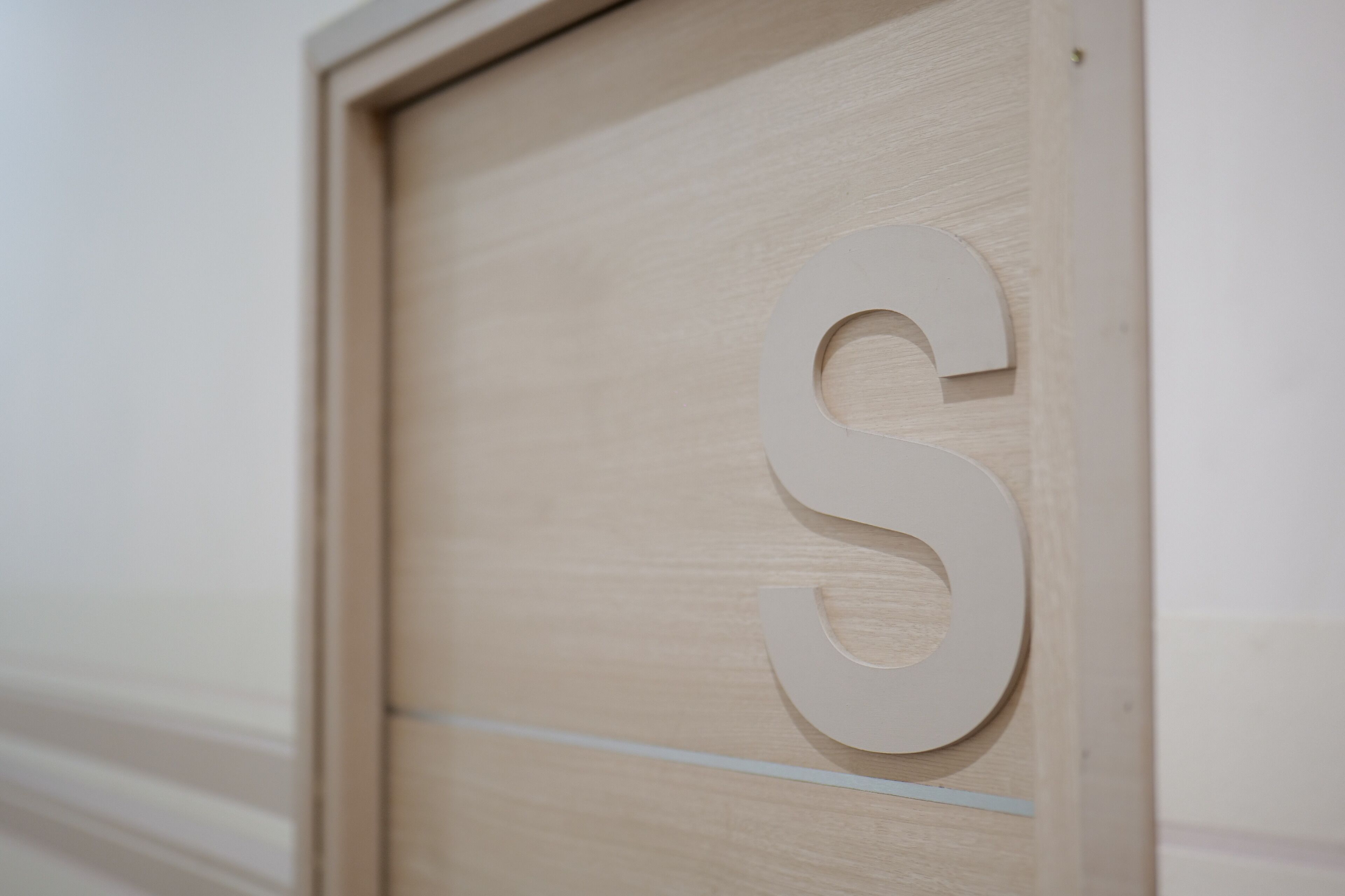 Een houten deur met een groot, wit 'S' uitgesneden.