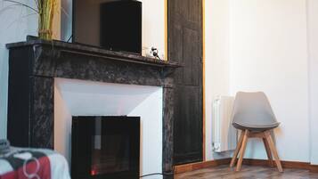 Un salon moderne avec une cheminée, un téléviseur et un fauteuil.