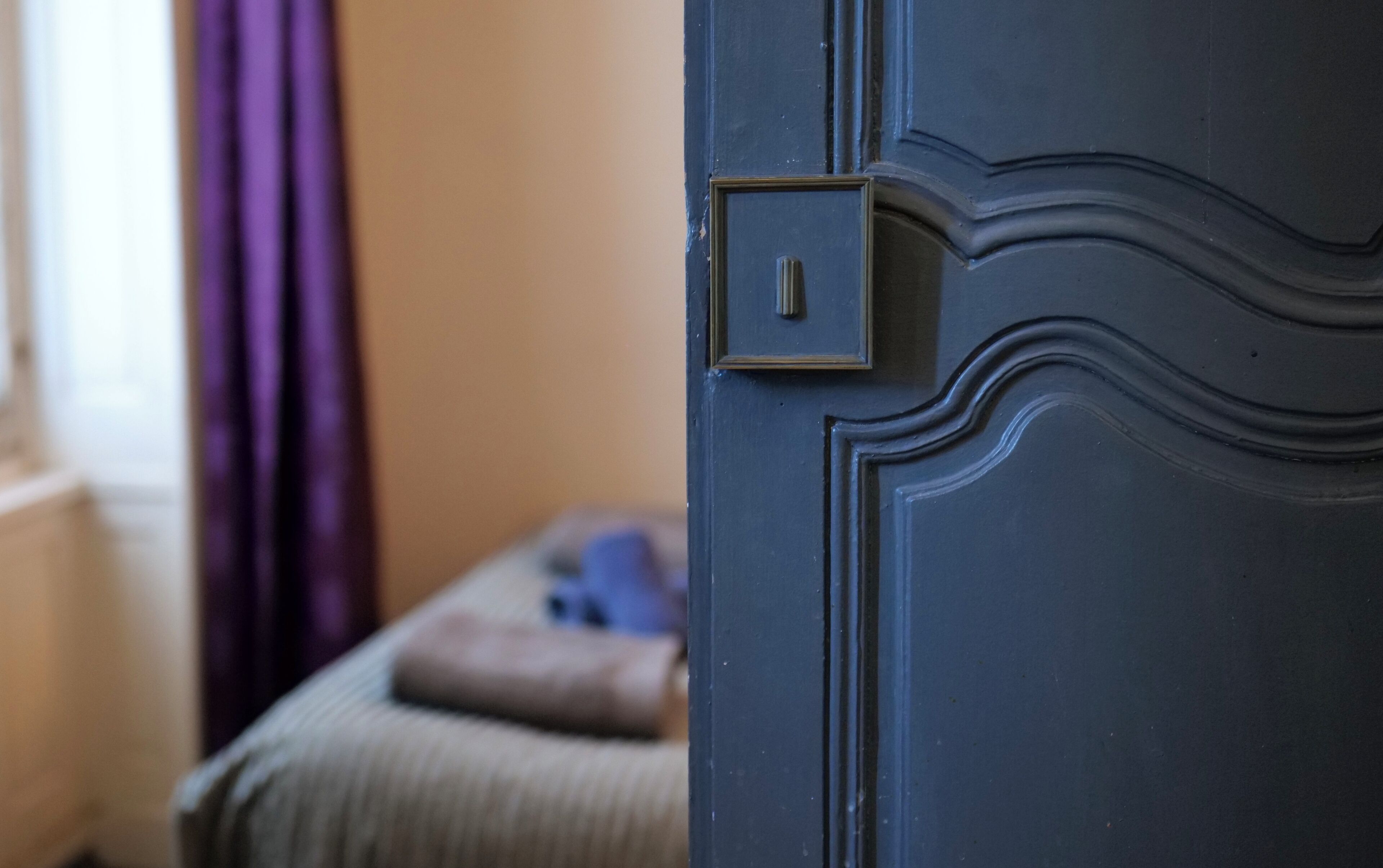 A close-up of a dark blue door with a textured pattern and a small square lock.