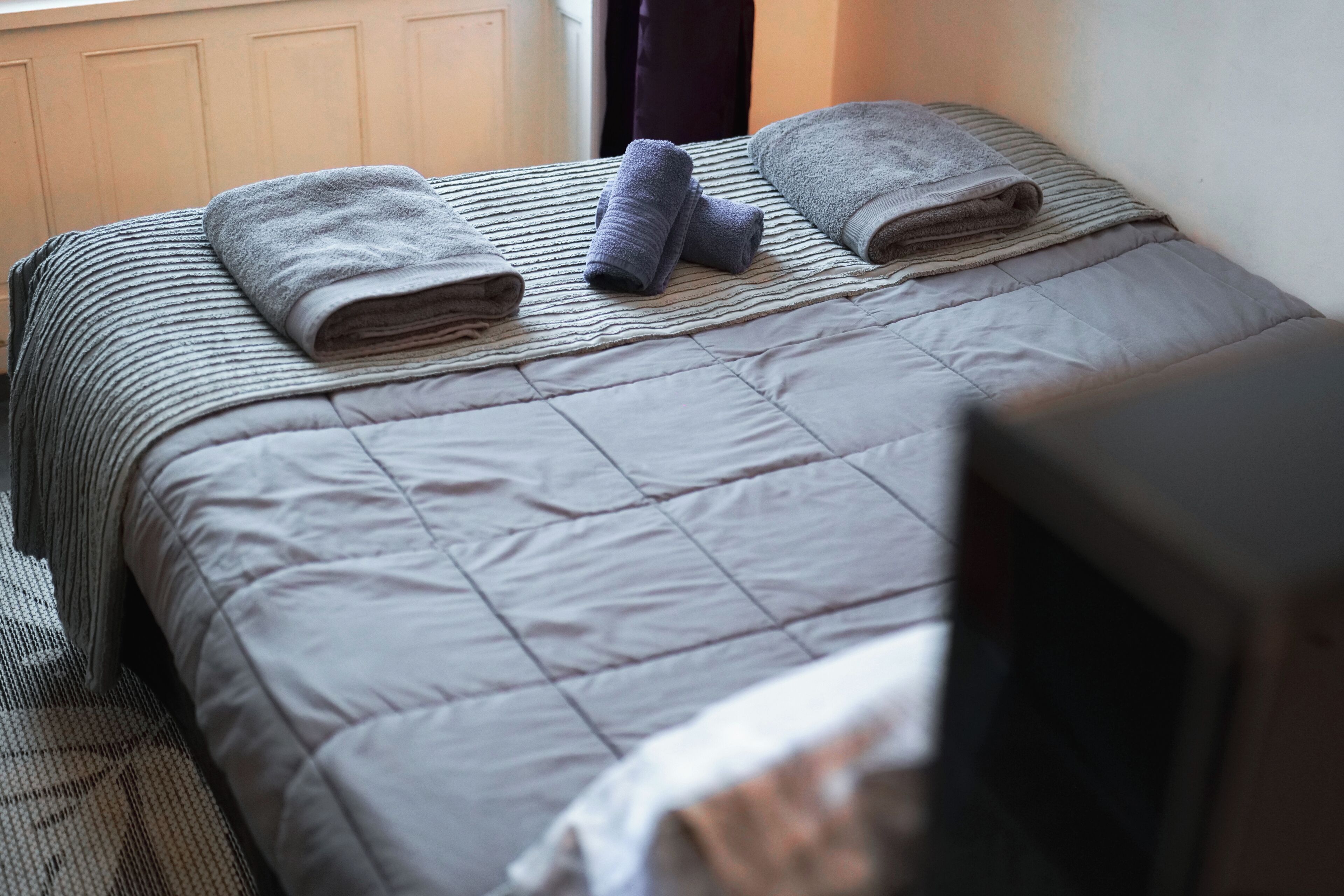 A neatly made bed with a striped bedspread and two folded towels.