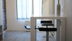 A modern room with a white table and two black chairs. A vase is on the table. - Les Cinq Lys (Carcassonne)