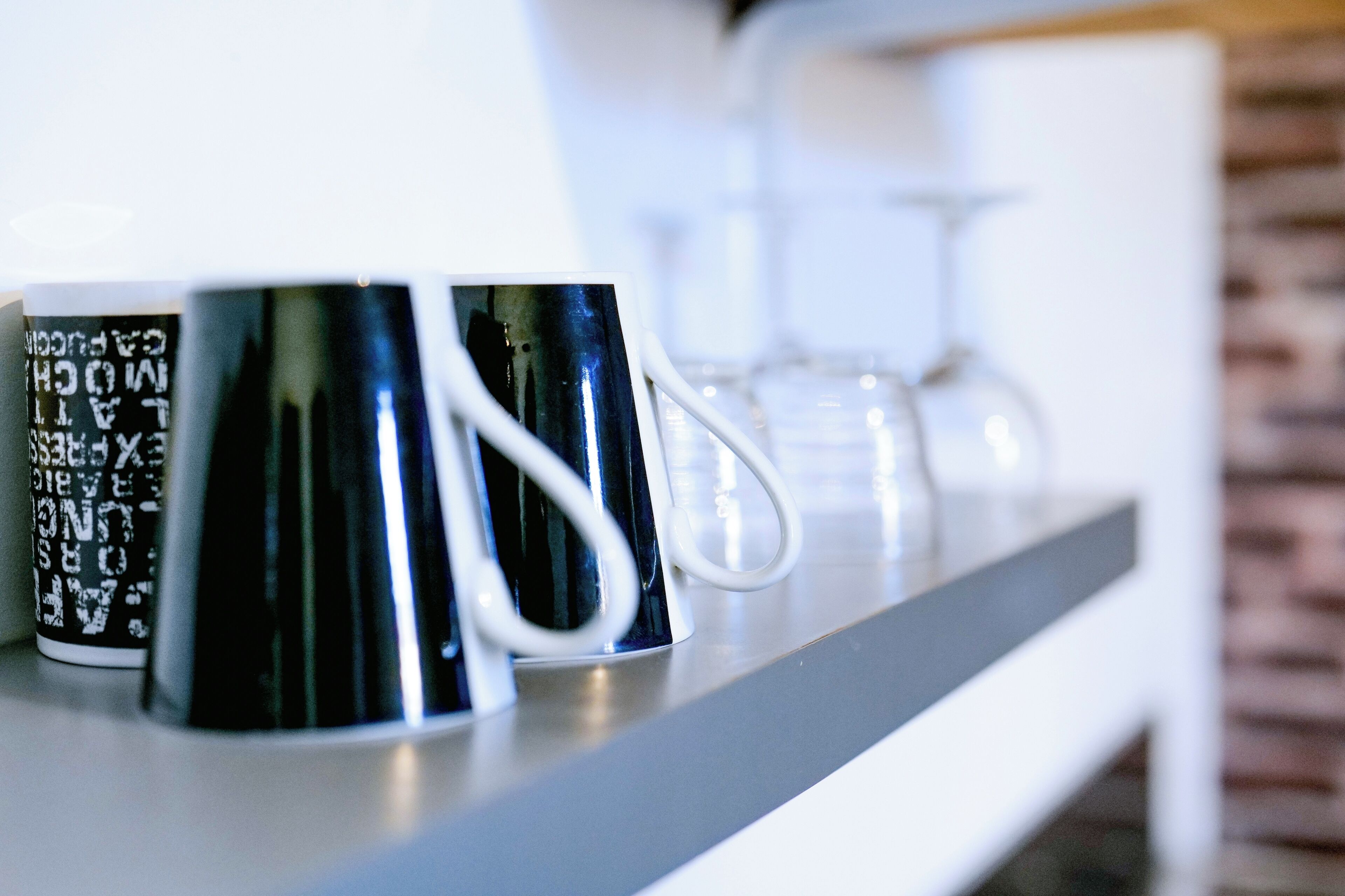 A row of black and white mugs on a shelf.