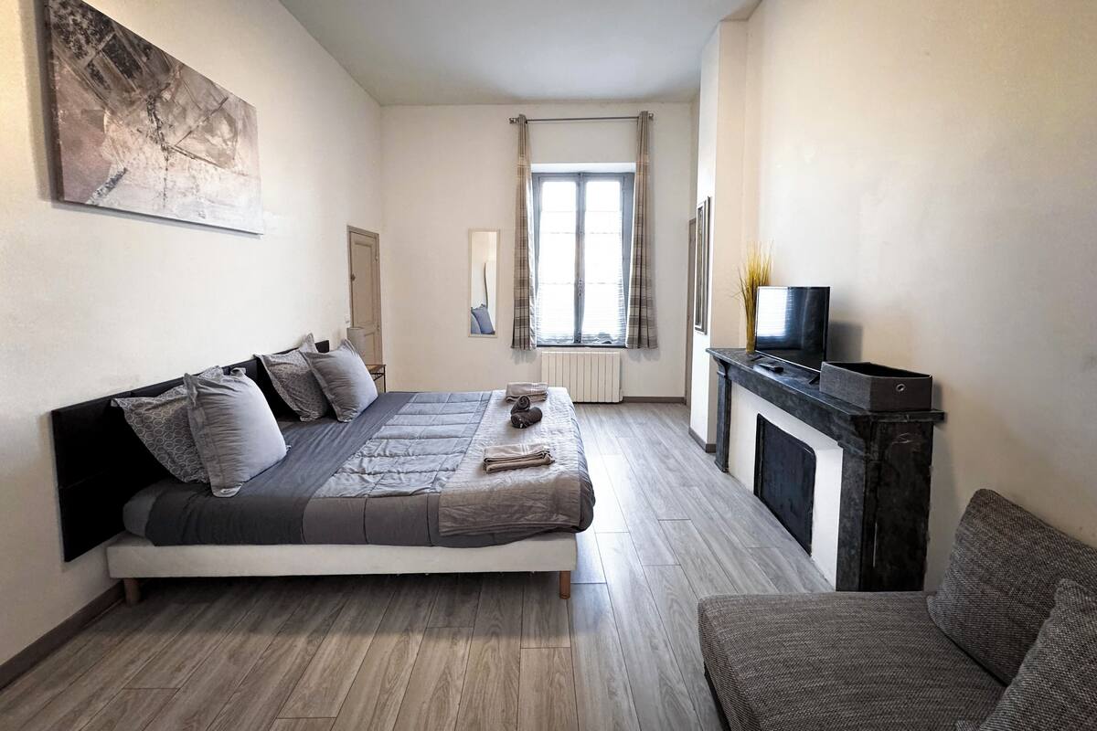 Un dormitorio con cama, televisión, chimenea y ventana con cortinas.