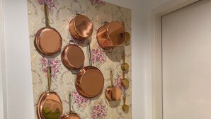 Eine Wand mit Kupferkochgeschirr und blumigem Wandpapier.