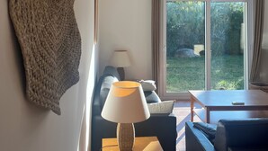 Ein modernes Wohnzimmer mit großem Fenster, einer Couch, einer Lampe und einem strukturierten Wandbild.
