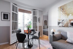 Una sala de estar moderna con comedor, ventanas abiertas y un cuadro grande en la pared.