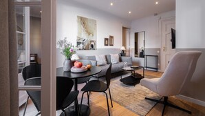 A modern living room with a sofa, dining table, chairs, and a TV. - CASA CALABRIA 2 BEDROOM 4 PAX (Barcelona)