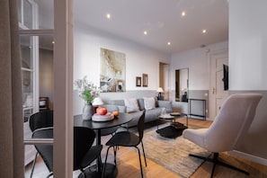 Una sala de estar moderna con un sofá, una mesa de comedor, sillas y un televisor.