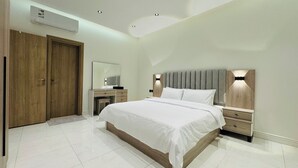 A modern bedroom with a large bed, wooden wardrobe, and a mirror. - Spacious & New 4-bedroom apartment in peaceful Madinah with AC, Fast-WiFi (Madinah)