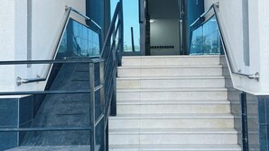 A modern building entrance with a glass facade, a set of stairs, and a metal railing. - Spacious & New 4-bedroom apartment in peaceful Madinah with AC, Fast-WiFi (Madinah)