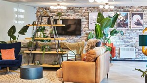 Un salon moderne avec un mur en briques, un téléviseur et diverses plantes.