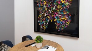 A conference room with a round wooden table, colorful chairs, and a large abstract painting on the wall. - Cozy apartment in marvelous Athina  (Athina)