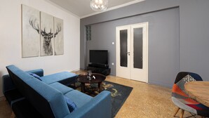 A modern living room with a sectional sofa, a coffee table, a TV, and a patterned rug. - Cozy apartment in marvelous Athina  (Athina)
