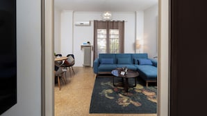 A living room with a blue sofa, a round coffee table, and a floral rug. - Cozy apartment in marvelous Athina  (Athina)