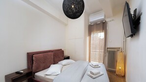 A modern hotel room with a bed, bedside table, and a television mounted on the wall. - Cozy apartment in marvelous Athina  (Athina)