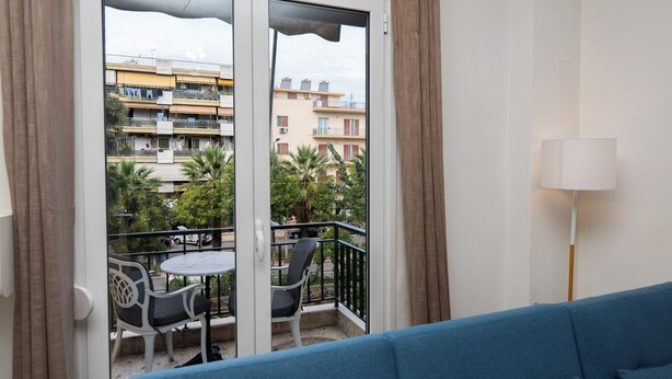 A balcony with a blue sofa, a table, and two chairs. - Cozy apartment in marvelous Athina  (Athina)