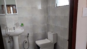 Un baño pequeño con un lavamanos blanco, inodoro y ducha.