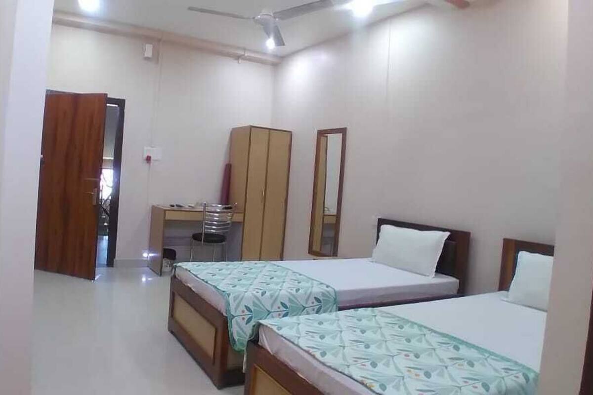 Une chambre avec deux lits, une armoire, un bureau et une chaise.