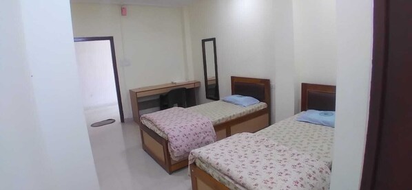 A room with two single beds, a desk, a chair, and a mirror. - Hotel Royal Residency Assam By GRB (Dergaon Circle)
