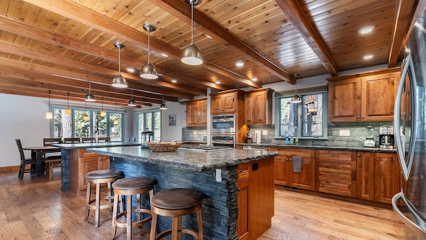 Una cocina amplia con armarios de madera, una isla grande con taburetes e iluminación colgante.