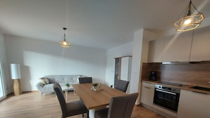 Une cuisine moderne avec des meubles en bois, une table à manger avec des chaises et des luminaires suspendus.