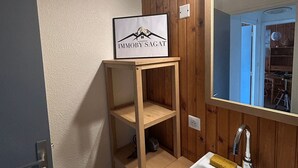 A wooden shelf with a framed sign in a bathroom with wooden paneling and a large mirror.