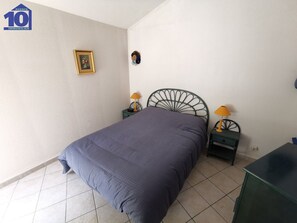 A bedroom with a single bed, two nightstands, a green metal headboard, a framed picture on the wall, and a small decorative item above the headboard. - 7 pers lodge with pool, AC, parking in Valras-Plage (Valras-Plage)