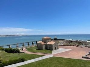A coastal view with a stone building, a pier, and a lighthouse.