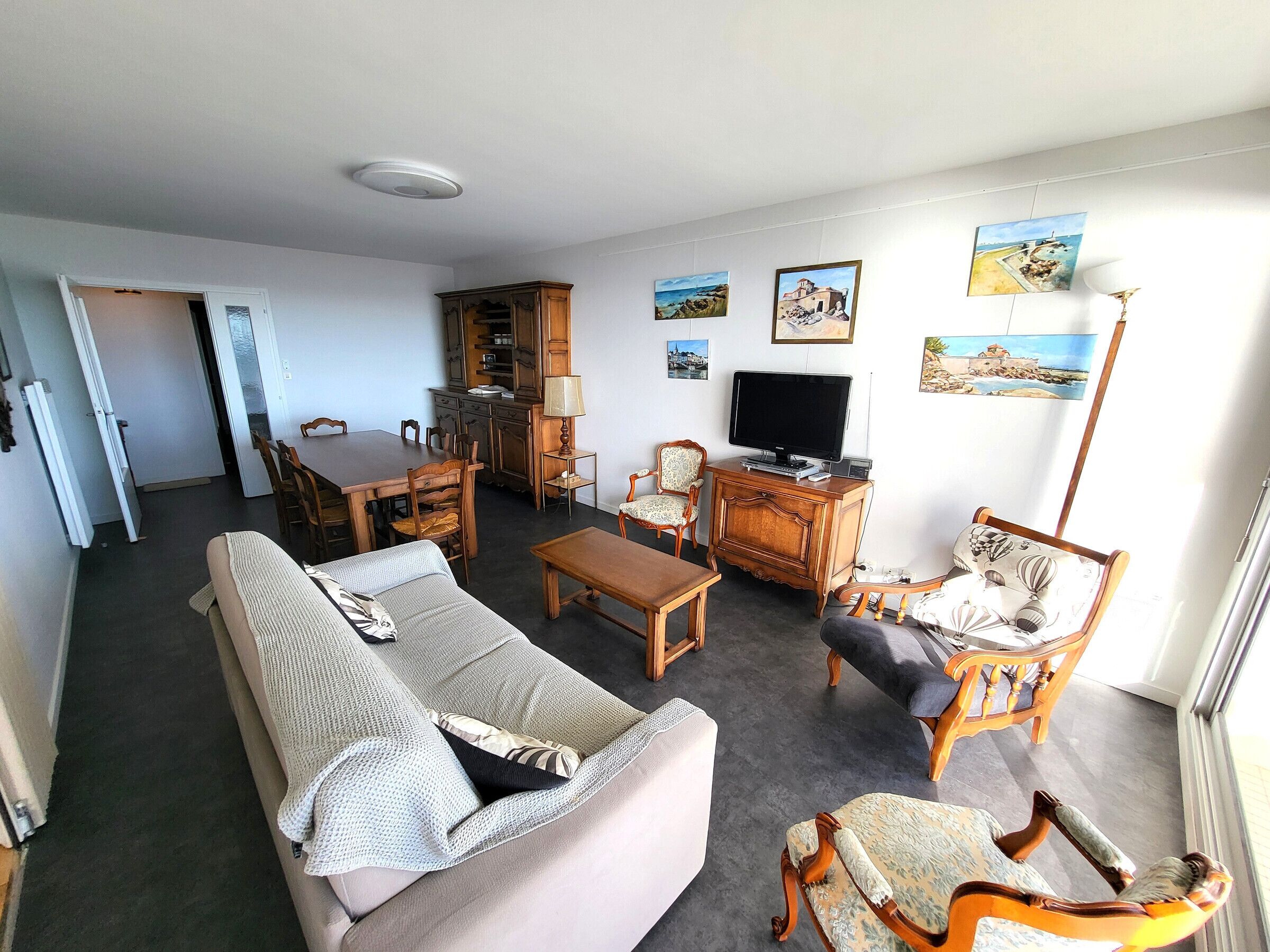 A living room with a sofa, armchairs, a coffee table, a TV, and a dining area with a table and chairs.