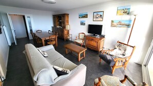 A living room with a sofa, armchairs, a coffee table, a TV, and a dining area with a table and chairs. - Seaside apartment with balcony, private parking in Les Sables-d'Olonne (Les Sables-d'Olonne)