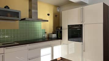 Une cuisine moderne avec des armoires blanches, une hotte de cuisinière en acier inoxydable et un dosseret de carrelage vert.