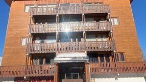 Un edificio de varios pisos con balcones, una entrada cubierta y cielo despejado.