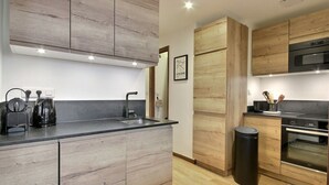 Una cocina moderna con armarios de madera, encimera negra y electrodomésticos de acero inoxidable.