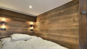 Un dormitorio con cabecera de madera, dos lámparas de noche y una cama con ropa blanca.