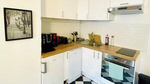 A compact kitchen with white cabinets, a black and white checkered floor, a dishwasher, a stove, and a sink. - Quiet, bright apartment in the heart of Paris 13 (Paris)