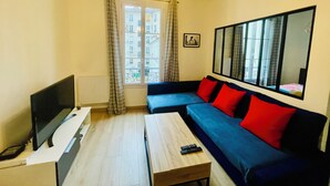 A living room with a TV, sofa, and wooden coffee table. - Quiet, bright apartment in the heart of Paris 13 (Paris)