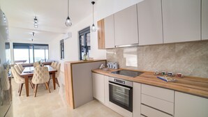 Een moderne keuken met een houten aanrecht, roestvrijstalen apparatuur en een eethoek met een grote tafel en stoelen.