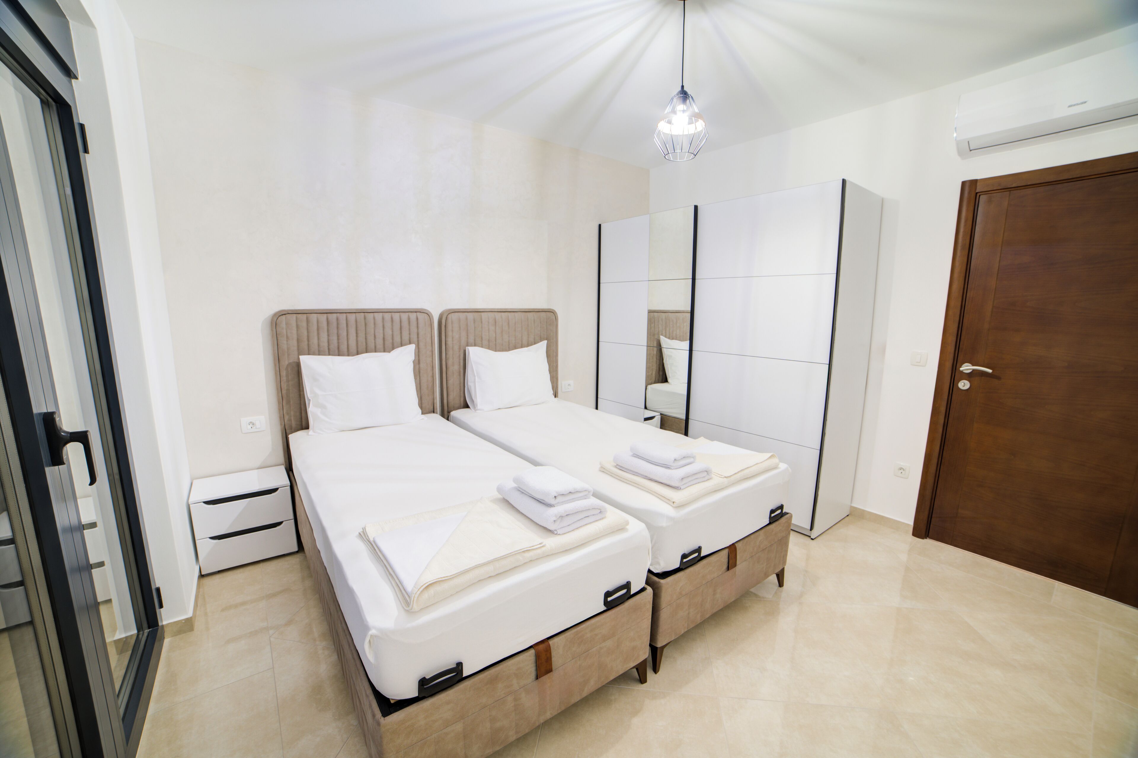 Quarto moderno com uma cama grande, um guarda-roupa, um espelho e uma porta.